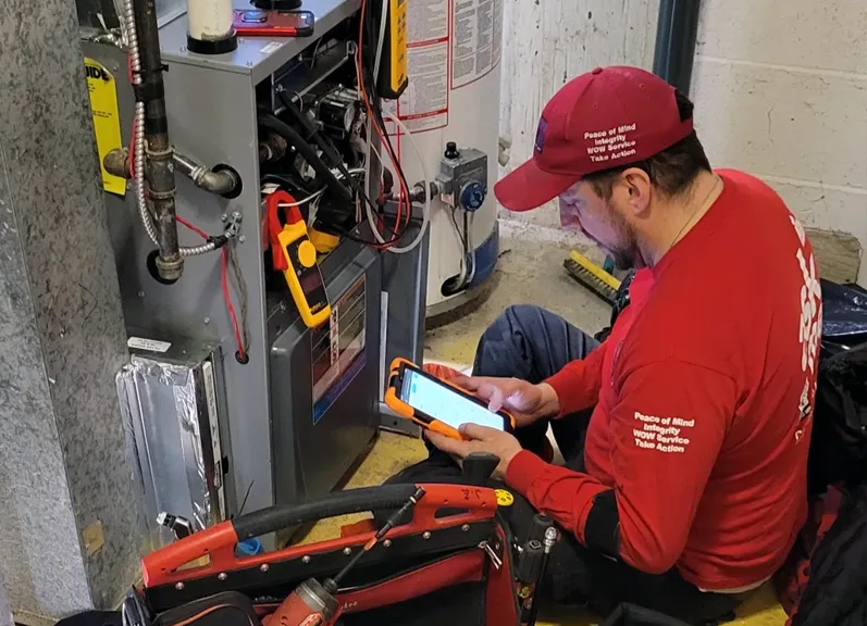 Technician performing maintenance on a high-efficiency gas furnace in Calgary